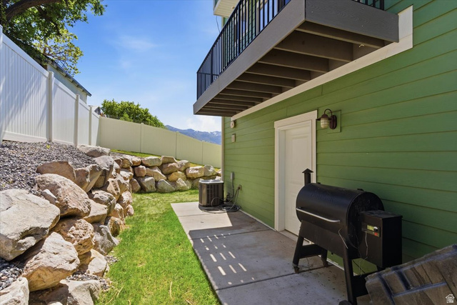 370 West Knights Lane Layton, UT 84041 - Photo 3 of 31 Backyard patio featuring green siding, a white privacy fence, and a rock retaining wall