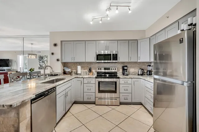 a kitchen with stainless steel appliances granite countertop a refrigerator sink and white cabinets