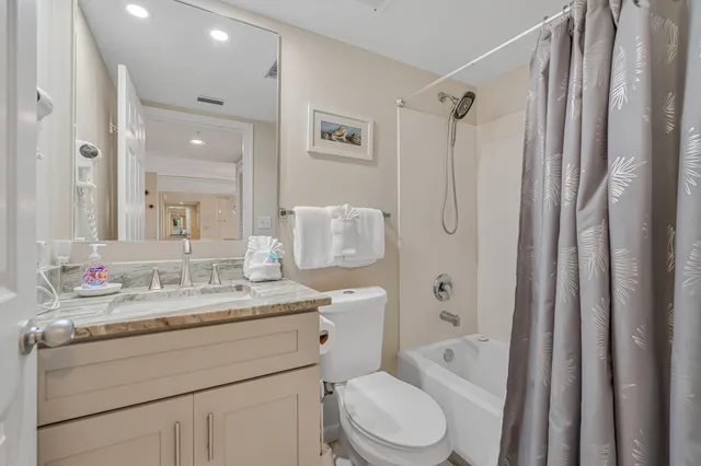 a bathroom with a granite countertop sink toilet a shower a mirror and a bathtub