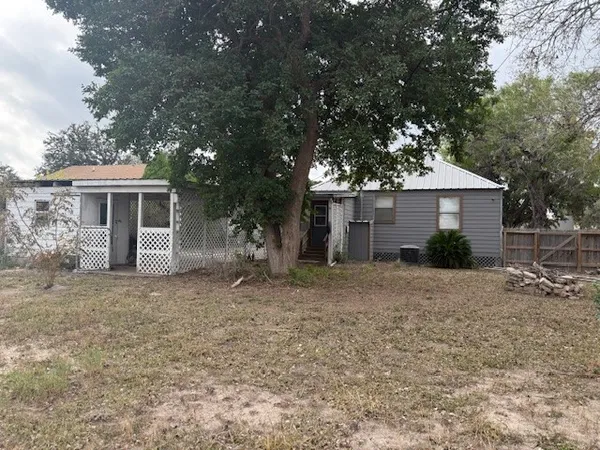 a view of a house with a yard and large tree