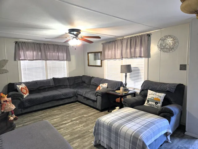 a kitchen with stainless steel appliances a stove a microwave a dining table and chairs with wooden floor