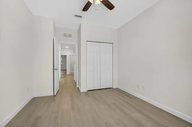 an empty room with closet and a ceiling fan