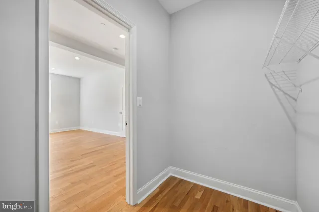a view of empty room with wooden floor and fan