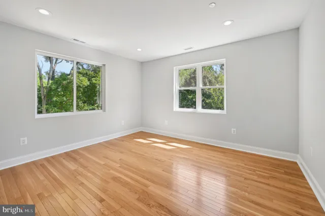 an empty room with wooden floor and windows