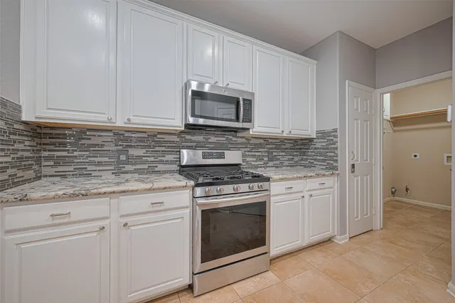 a kitchen with granite countertop white cabinets and stainless steel appliances