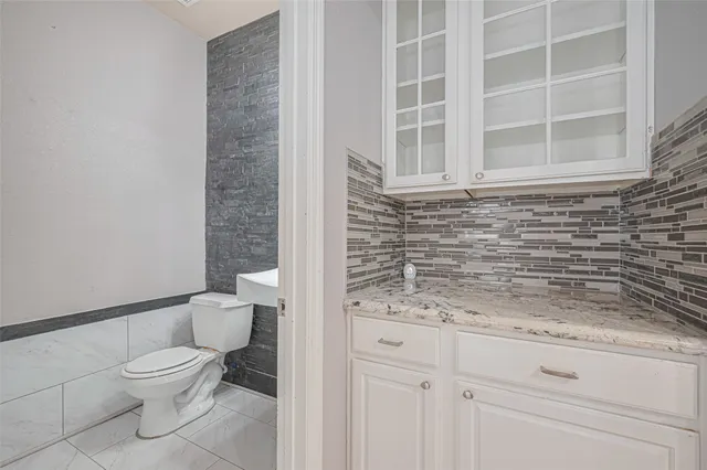 a bathroom with a granite countertop toilet and a sink