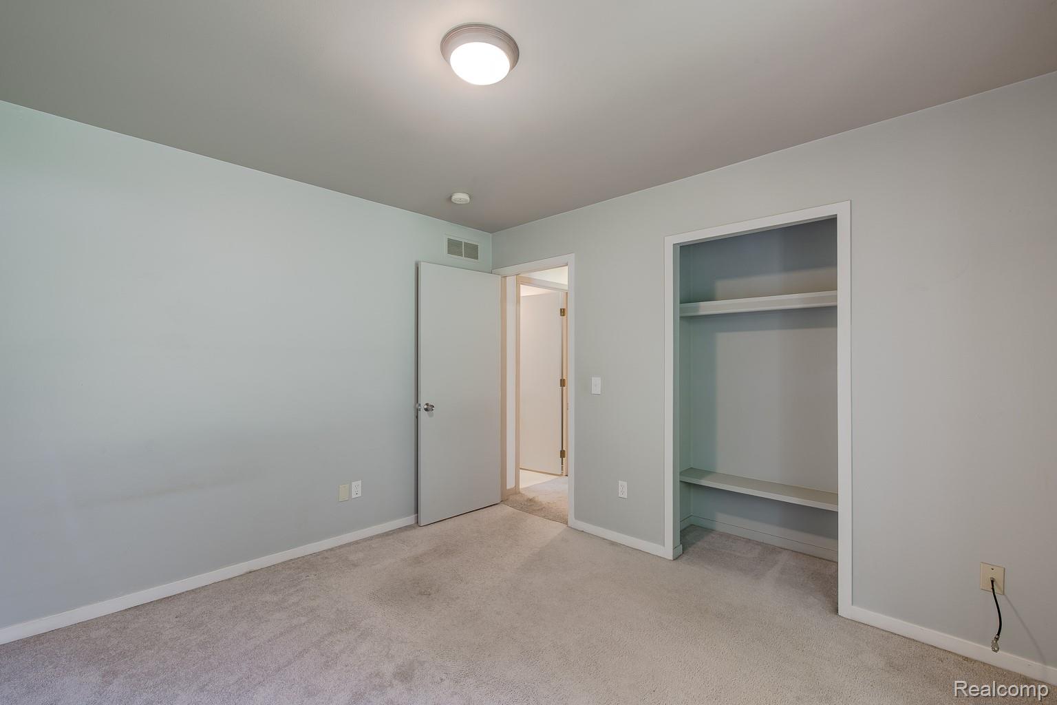 312 Reid Road Highland, MI 48357 - Photo 29 of 47 Carpeted room with light grey walls, a flush-mount ceiling light fixture, and an open doorway