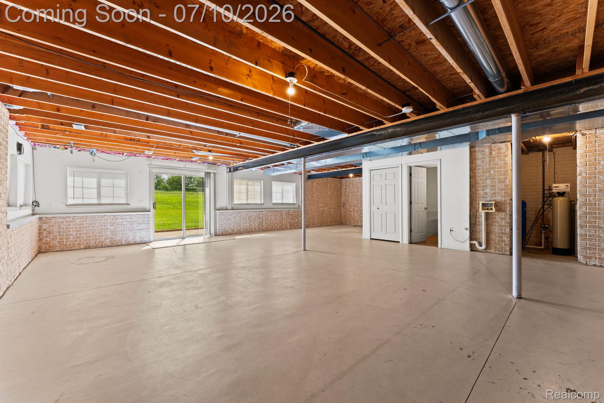 3144 North Nicholson Road Fowlerville, MI 48836 - Photo 63 of 70 Expansive unfinished basement featuring a walk-out patio door, multiple egress windows, exposed wood ceiling joists, and a concrete floor
