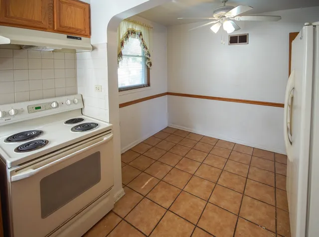 an empty room with wooden floor and ceiling fan