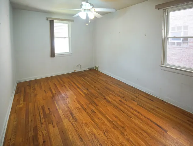 an empty room with wooden floor and bathroom view