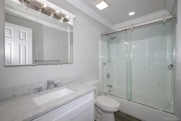 a bathroom with a granite countertop sink toilet mirror and shower