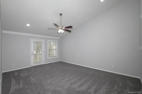 a view of an empty room with chandelier fan and fire place