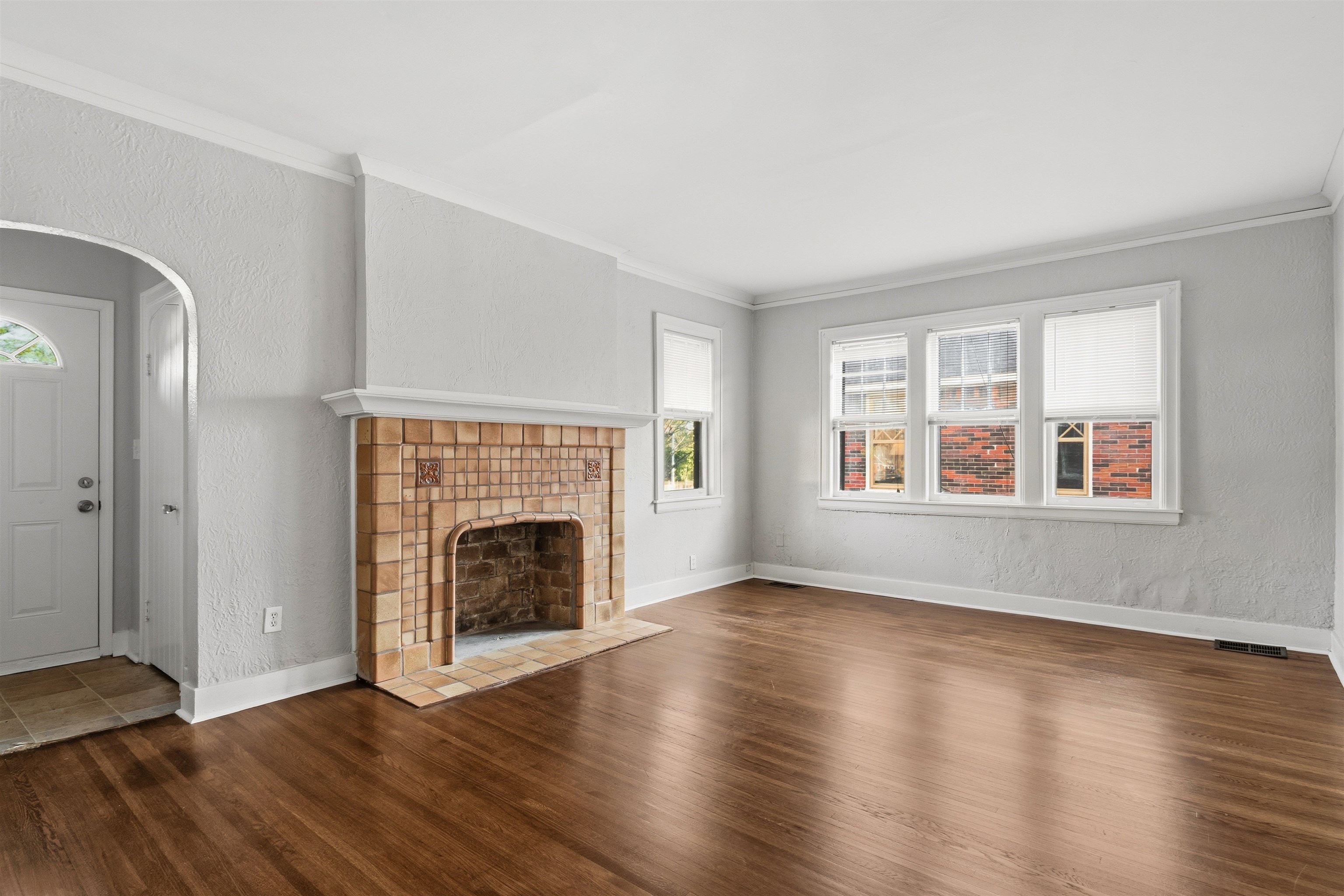 871 University Street Memphis, TN 38107 - Photo 5 of 26 an empty room with wooden floor fireplace and windows