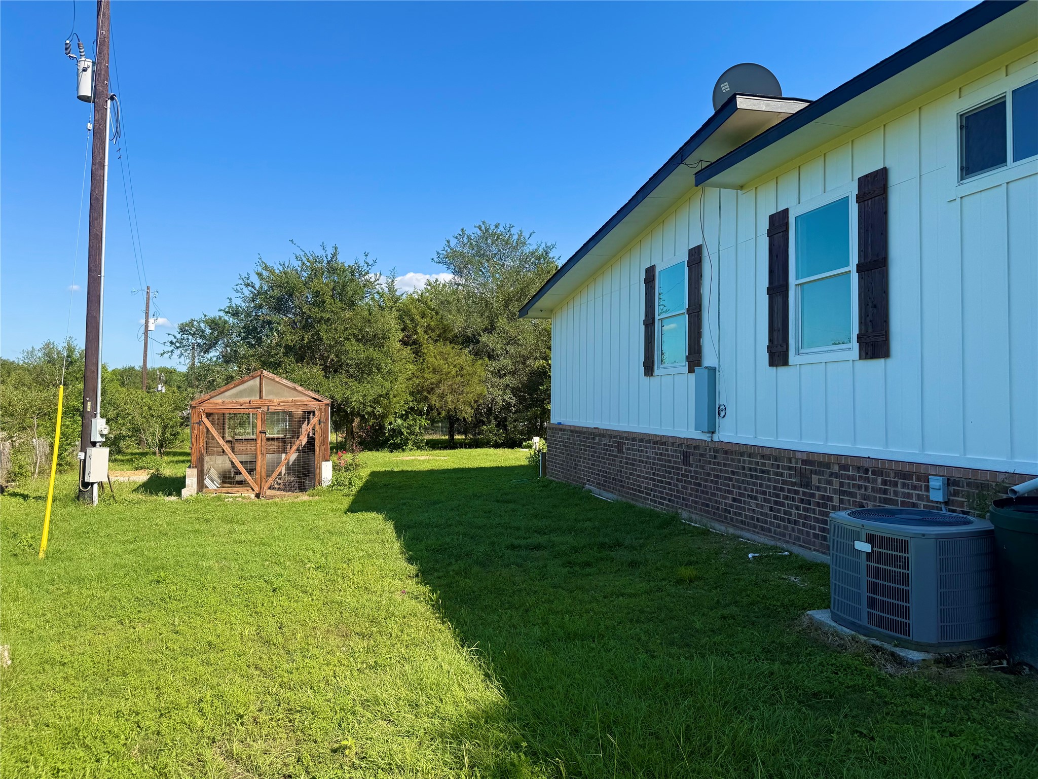 739 Pleasant Grove Road Elgin, TX 78621 - Photo 24 of 29 White board-and-batten siding with dark shutters and a brick foundation