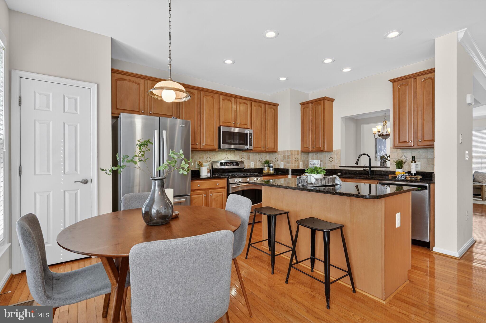 9144 Furey Road Lorton, VA 22079 - Photo 11 of 28 a kitchen with stainless steel appliances granite countertop a refrigerator a stove top oven a sink dishwasher and a dining table with wooden floor