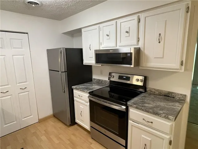 a kitchen with white cabinets and stainless steel appliances