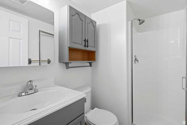 3732 Campbell Road Tooele, UT 84074 - Photo 27 of 69 Bathroom featuring a white vanity with a chrome faucet, wall-mounted mirror, and a shower stall with a glass enclosure