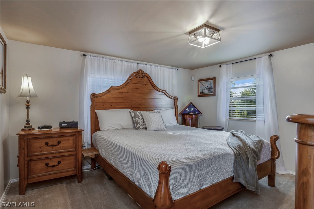 23751 North River Road Alva, FL 33920 - Photo 15 of 34 a bedroom with a bed and a chandelier