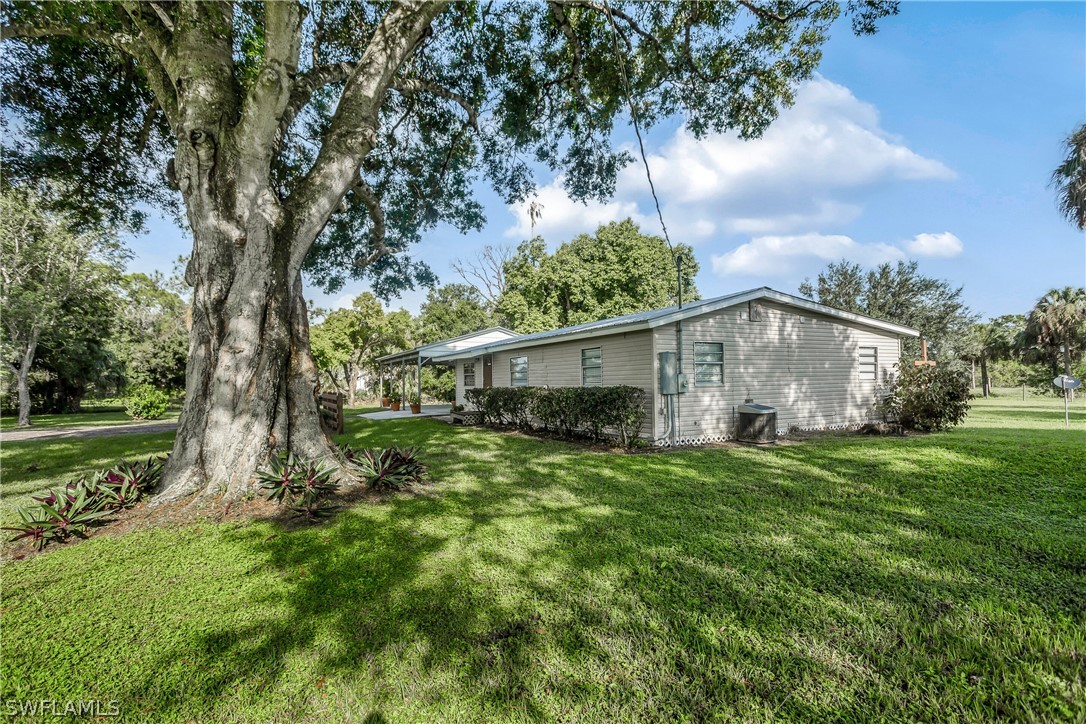 23751 North River Road Alva, FL 33920 - Photo 24 of 34 a view of a house with a big yard potted plants and large tree