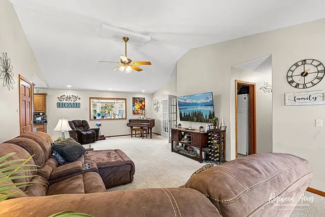 a living room with furniture a flat screen tv and a refrigerator