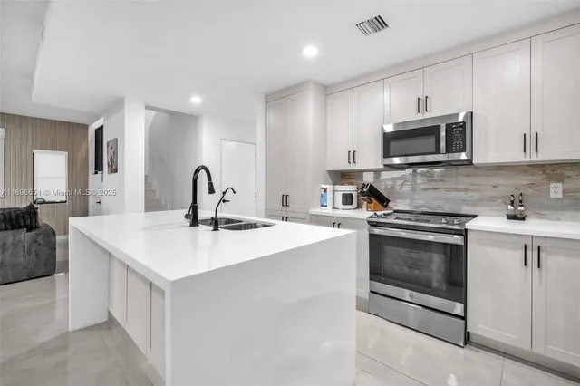a kitchen with a dining table chairs refrigerator and white cabinets