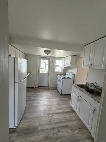 a kitchen with sink a refrigerator and white cabinets