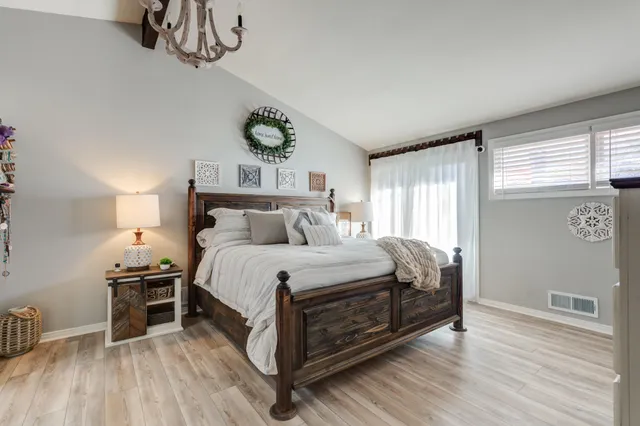 a spacious bedroom with a bed and a flat tv screen on dresser