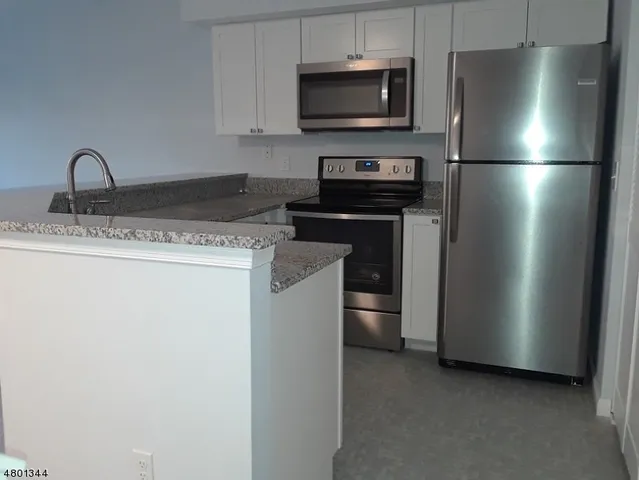 a kitchen with stainless steel appliances granite countertop a refrigerator and a stove top oven