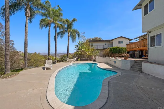 a view of a swimming pool with a lawn chairs under palm trees