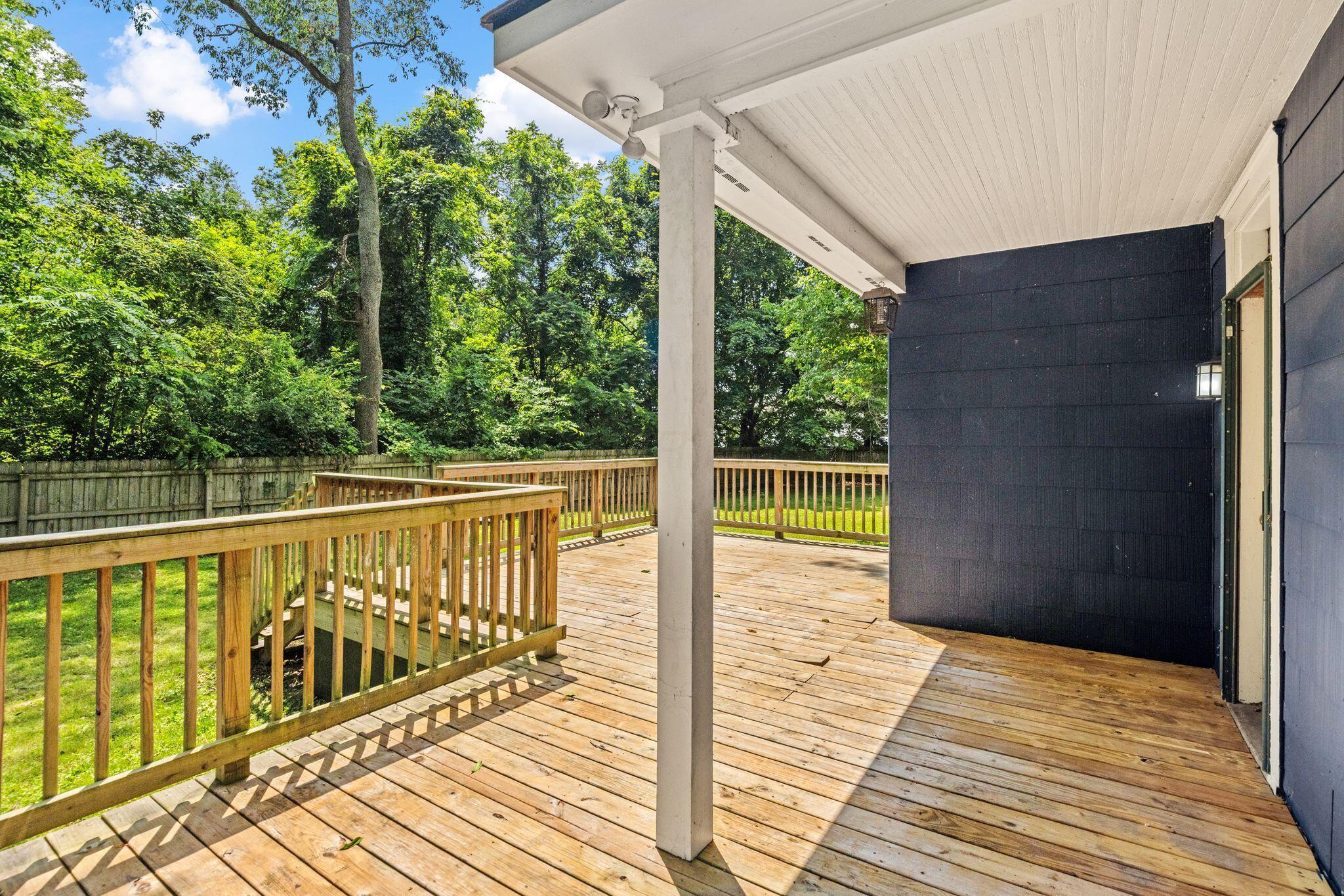 107 Price Road Columbus, OH 43230 - Photo 32 of 51 Expansive wood deck with a built-in railing system, covered porch area featuring a white beadboard ceiling, and dark exterior siding
