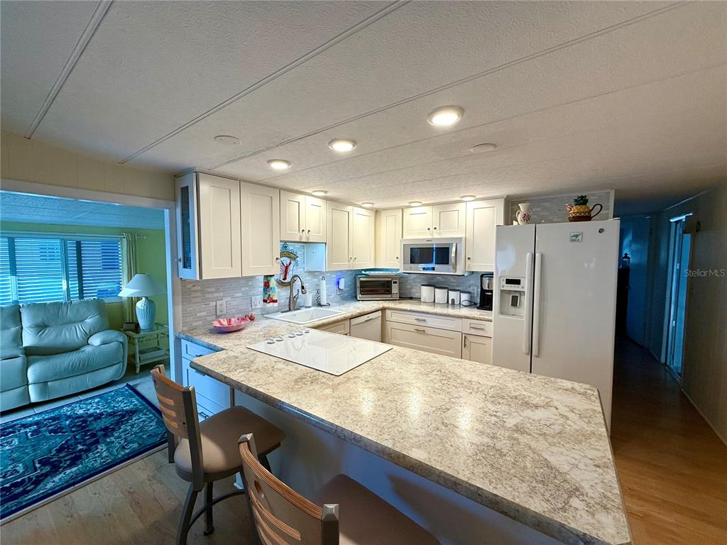 6091 Peony Road Venice, FL 34293 - Photo 4 of 12 a kitchen with stainless steel appliances granite countertop a table chairs sink refrigerator and cabinets