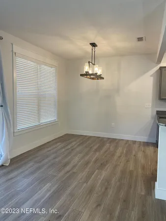 a view of empty room with wooden floor chandelier and window
