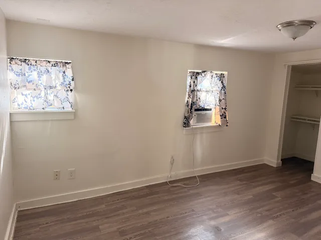 an empty room with wooden floor and window