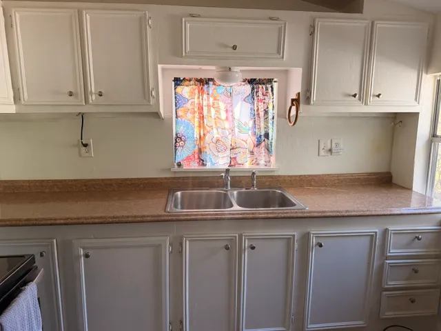 a kitchen with granite countertop white cabinets and sink