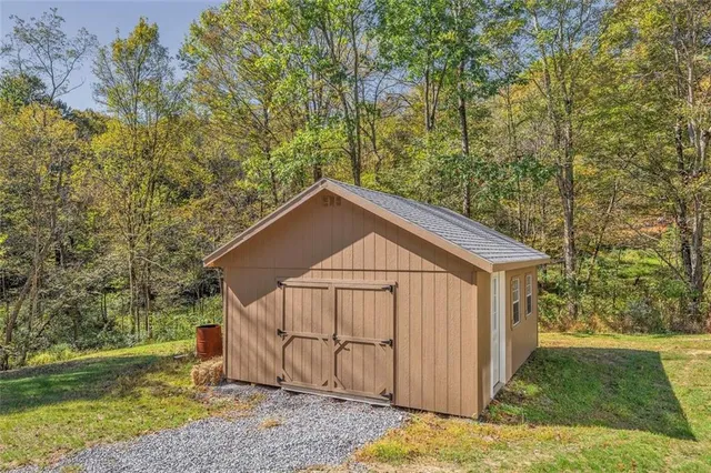 a view of a small house with a big yard and large trees