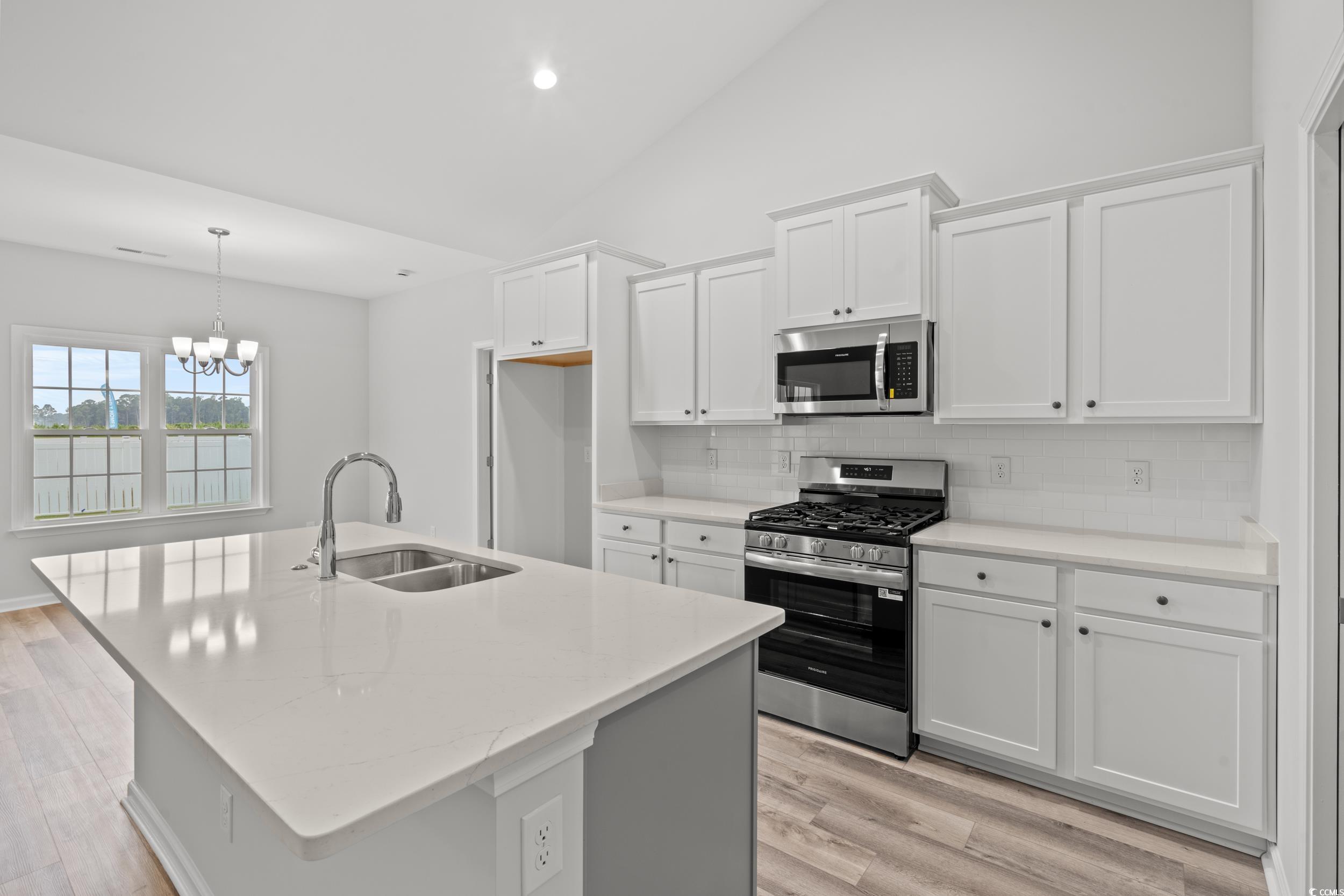 267 Stillbrook Drive Longs, SC 29568 - Photo 2 of 37 Kitchen with appliances with stainless steel finishes, white cabinets, an island with sink, light stone countertops, and backsplash