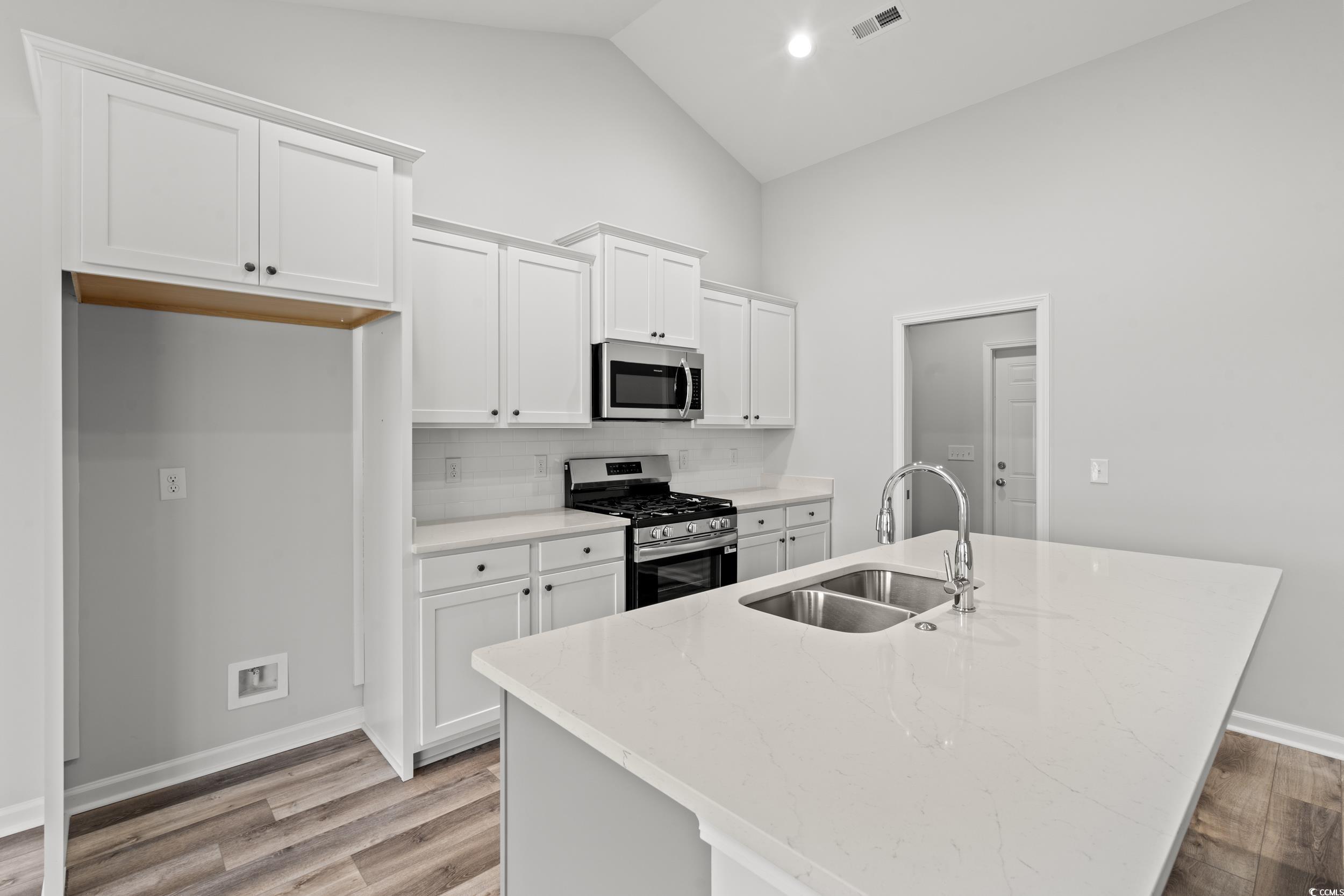 267 Stillbrook Drive Longs, SC 29568 - Photo 5 of 37 Kitchen with white cabinets, stainless steel appliances, light wood-style floors, light stone countertops, and a center island with sink