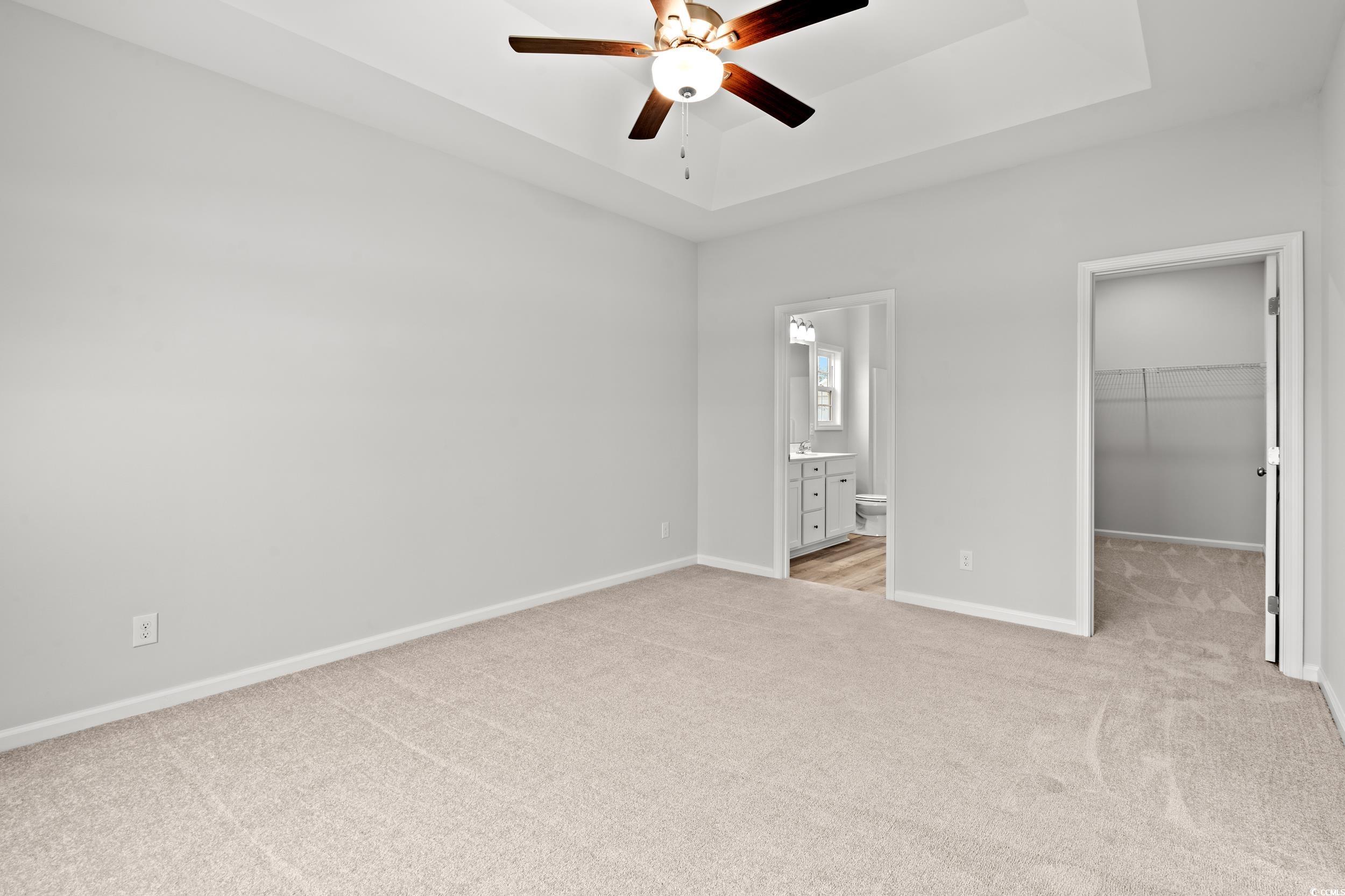 267 Stillbrook Drive Longs, SC 29568 - Photo 10 of 37 Unfurnished bedroom featuring a raised ceiling, light carpet, a walk in closet, and a ceiling fan