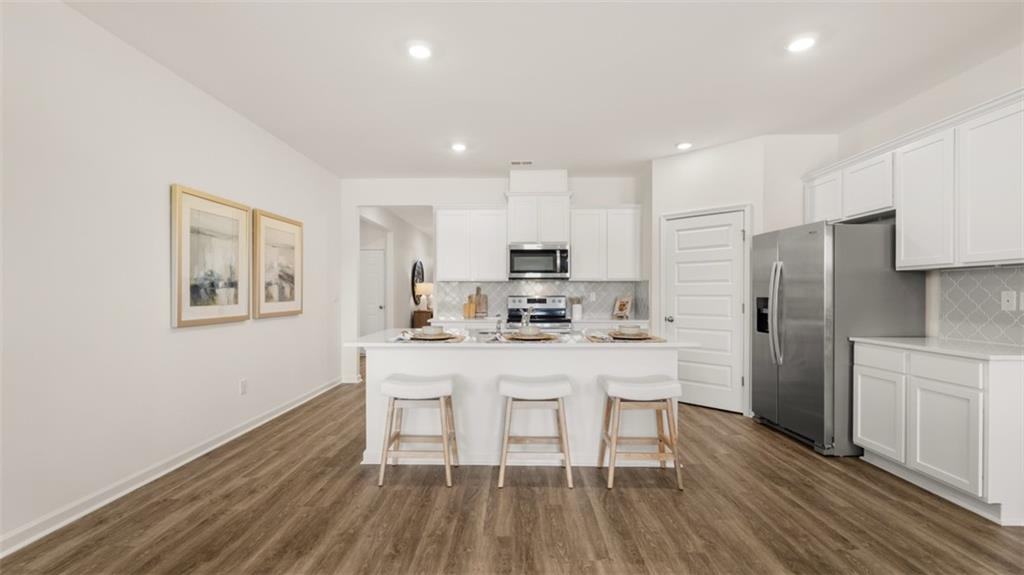 207 Cattle Drive Perry, GA 31069 - Photo 11 of 52 a kitchen with stainless steel appliances granite countertop a refrigerator a microwave oven a sink dishwasher and white cabinets with wooden floor