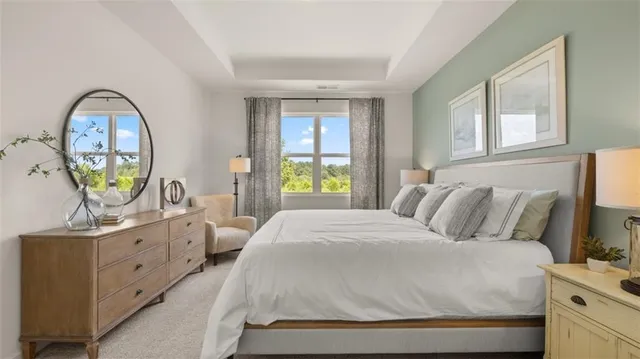 a bedroom with a bed a mirror on the dresser and a window