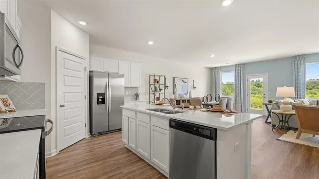 a kitchen with stainless steel appliances a refrigerator a stove top oven a sink dishwasher and a refrigerator with wooden floor