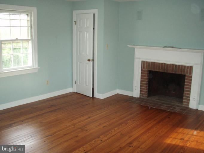 487 Rudasill Mill Road Woodville, VA 22749 - Photo 27 of 30 an empty room with wooden floor fireplace and windows
