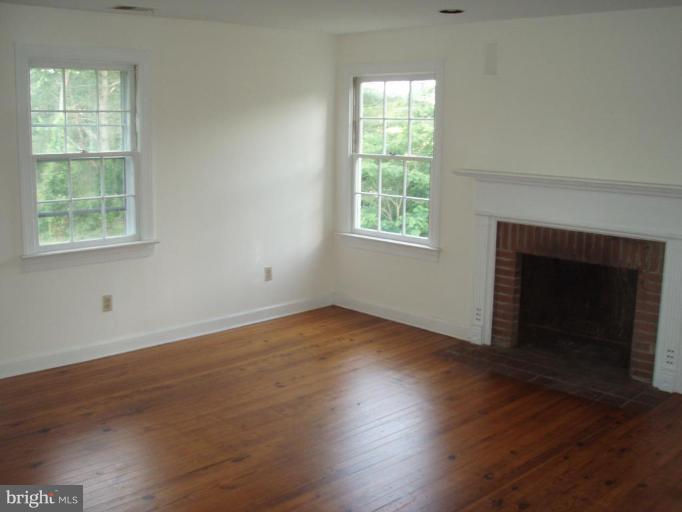 487 Rudasill Mill Road Woodville, VA 22749 - Photo 28 of 30 an empty room with wooden floor windows and fireplace
