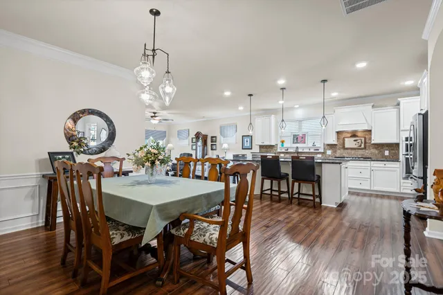 a dining room filled chandelier and wooden floor
