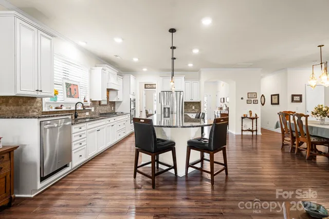 a kitchen with stainless steel appliances granite countertop wooden floor dining table and chairs