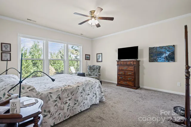 a spacious bedroom with a bed a dresser and a flat screen tv