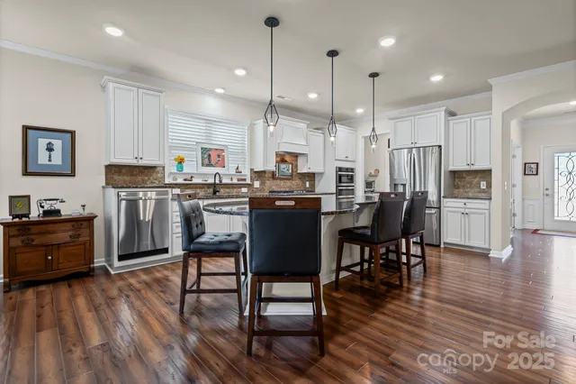 a kitchen with stainless steel appliances granite countertop wooden floors stove and white cabinets