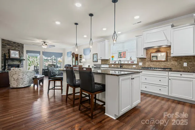 a kitchen with stainless steel appliances granite countertop wooden floors stove and white cabinets