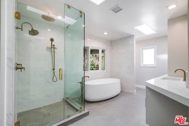 a spacious bathroom with a tub shower sink and mirror