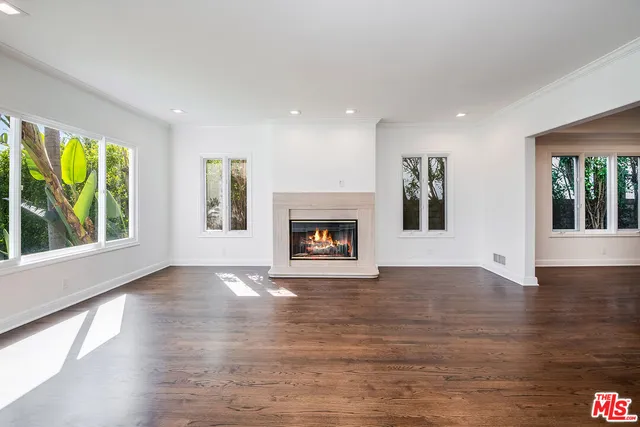 an empty room with large windows and a fireplace